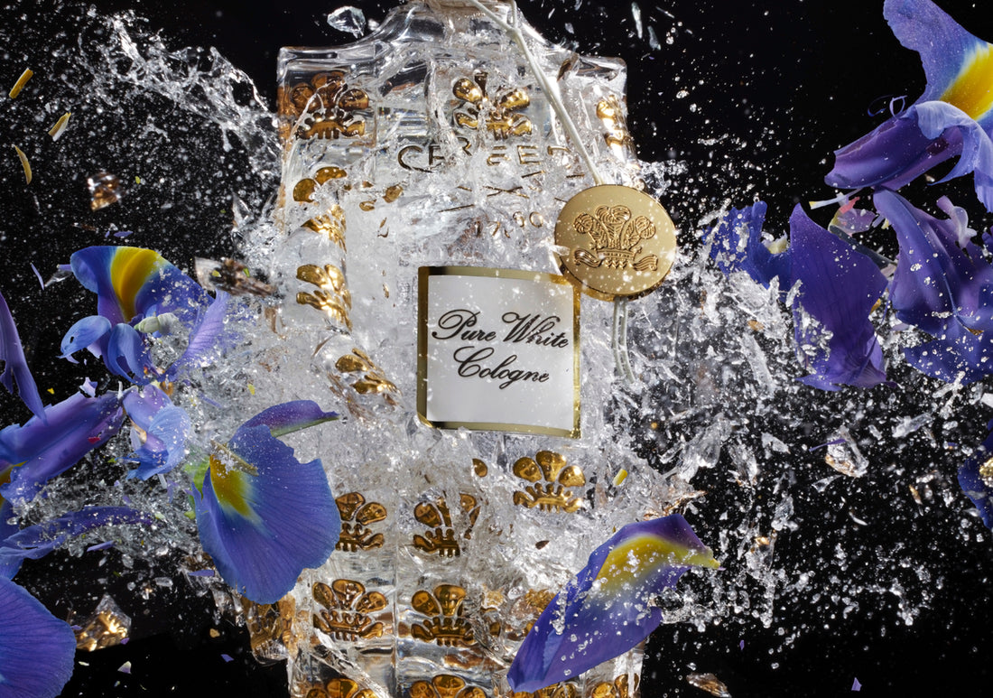 a bottle of pure white cologne exploding with liquid and flowers