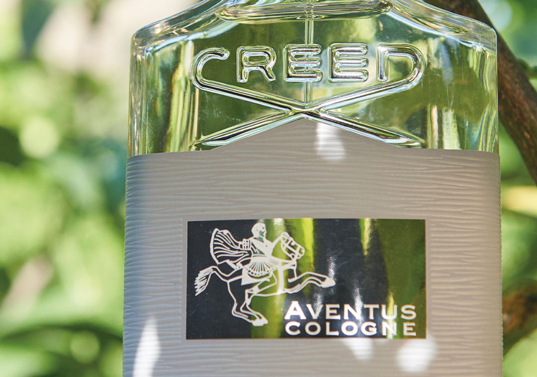 close up image of a bottle of aventus cologne with a leafy background