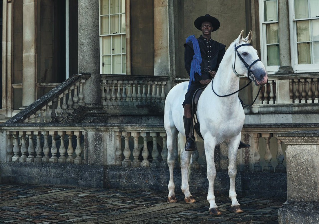 black man on a white horse outside stately home
