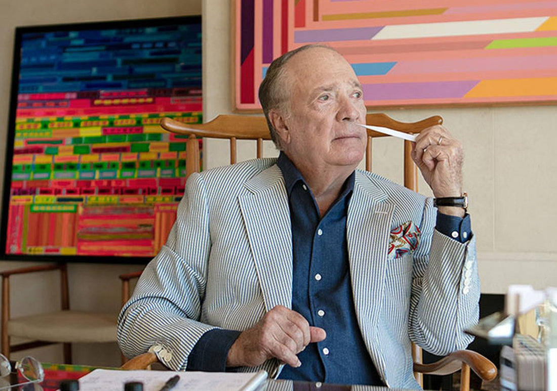 olivier creed sitting at a desk with artworks behind him