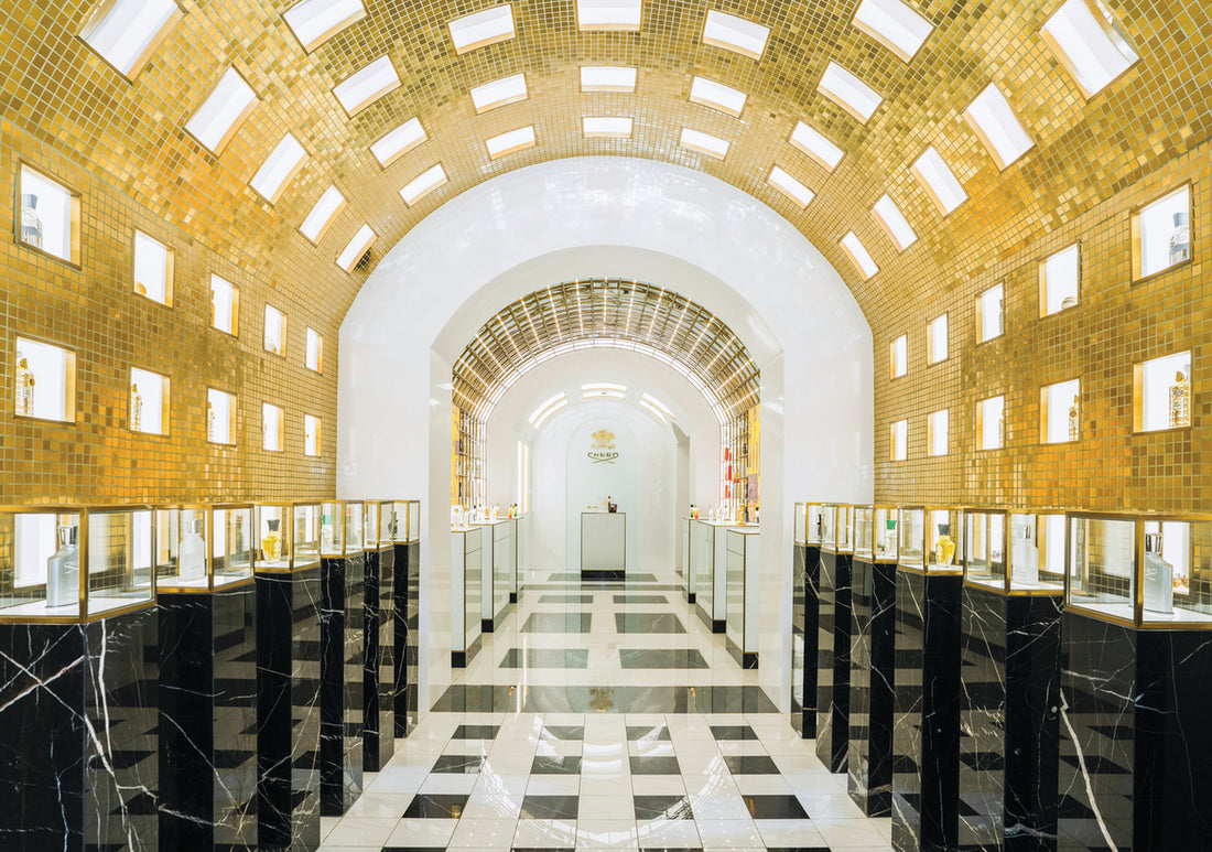interior of the creed boutique in Rome with gold tunnel ceiling, marble floors and black plinths with fragrances on top