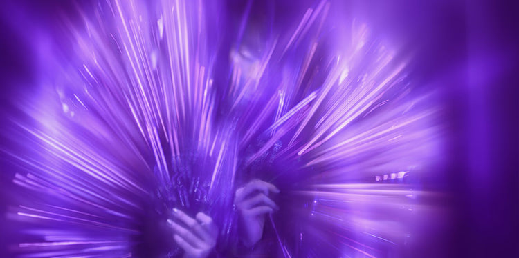 A woman moves her hands majestically creating a captivating purple haze.