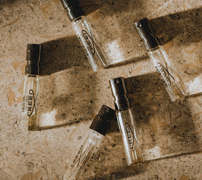 5 creed sample vials on a marble surface