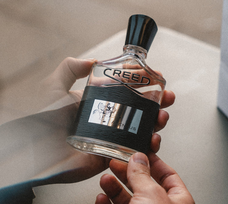 hands holding a Creed Aventus Bottle