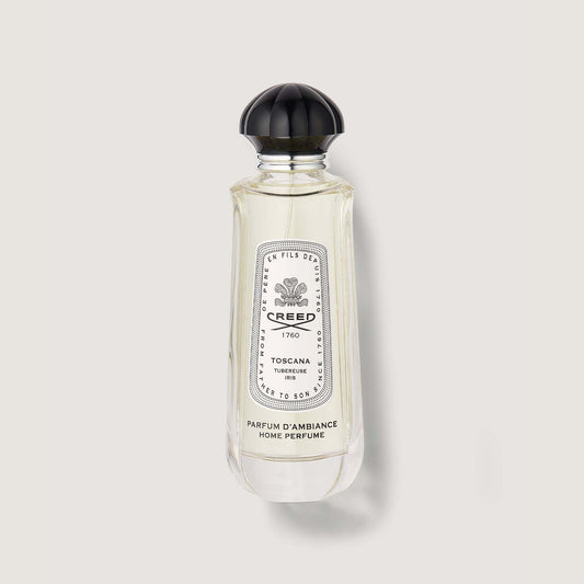 clear narrow bottle of Toscana room spray with black cap and white and black label